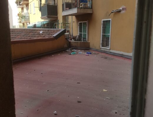 Vista di un cortile interno a Bologna con edifici residenziali gialli e balconi, che mostra un'area potenzialmente parte di 4Roomz & Yacht Club.