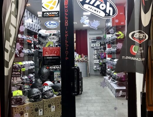 Ingresso del negozio 58 Rosso Bikers' Store a Genova, con vetrina piena di caschi Airoh, Arai e altri marchi di accessori moto. Negozio specializzato per motociclisti.