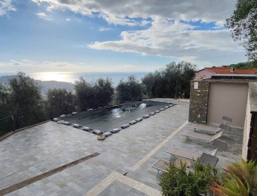 Vista panoramica di una piscina coperta in una villa con vista mare a Baracca du Pei, Liguria. Arredamento esterno e vegetazione rigogliosa.