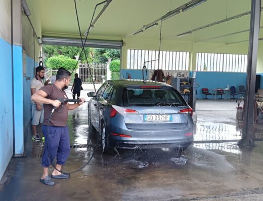 Lavaggio auto A.Quality: Uomo lava una station wagon grigia con idropulitrice, servizio di pulizia professionale per auto e moto.