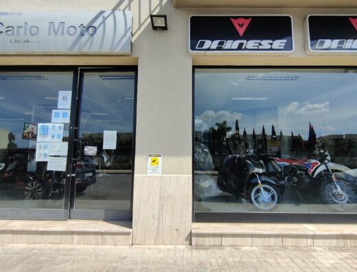 Showcase of Gaetano Di Carlo Sas, a motorcycle apparel and accessories store, with display of motorcycles and Dainese products.