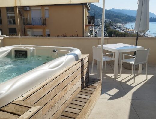 Abelia Sea Suites: Rooftop terrace featuring a jacuzzi with wooden surround, a white table with chairs, an umbrella, and a view of the beach and sea.