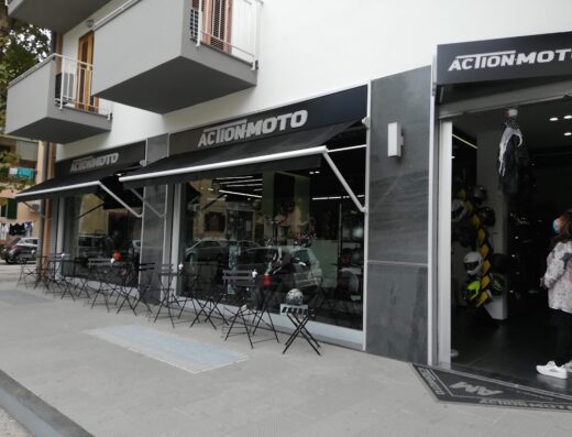 ActionMoto SRL negozio di accessori e abbigliamento per moto a Genova, con vetrine, tavolini esterni e ingresso con caschi esposti.