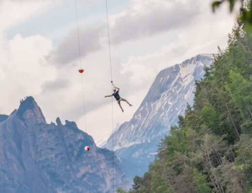 Un uomo che pratica zipline ad alta quota tra le montagne, un'esperienza estrema per amanti dell'avventura e della natura.