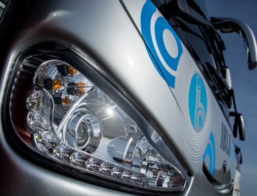 Faro anteriore di un autobus dell'agenzia viaggi Ibla Tour, con logo aziendale in blu. Servizi di trasporto e viaggi organizzati.