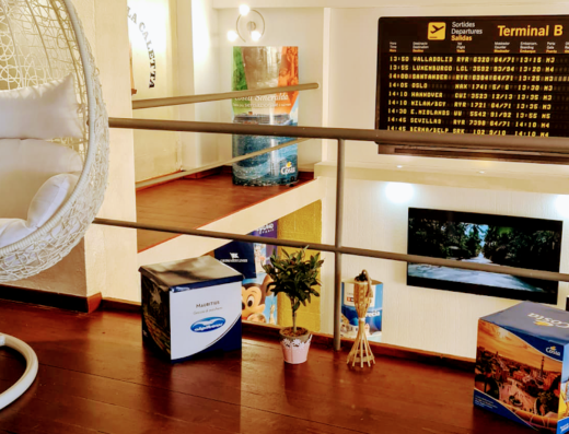 Interni dell'Agenzia Viaggi La Caletta di Piredda Noemi, arredamento con poltrona sospesa, tabellone partenze voli, espositori Costa Crociere e MSC Crociere per offerte viaggi e vacanze