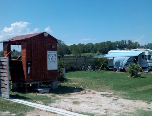 Agricampeggio Az.Vomano Vecchio: Veduta di una piccola struttura in legno e una roulotte in un'area verde, ideale per campeggio e relax all'aria aperta.