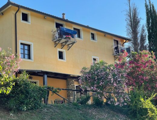 Agriturismo A Canonica: Vista esterna della struttura con balconi adornati e vegetazione fiorita, ideale per un soggiorno rilassante.