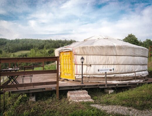 Yurta in legno con porta gialla all'Agriturismo Agricampeggio Società Agricola Cacigolara, ideale per vacanze e turismo rurale