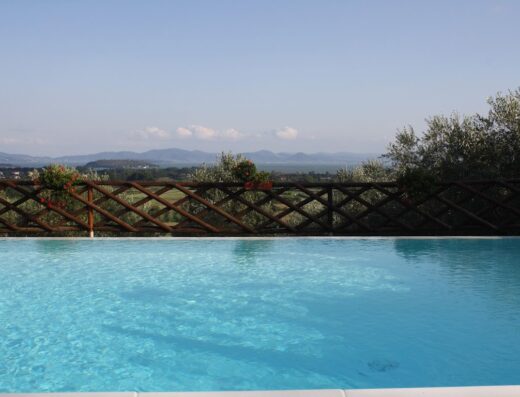 Piscina panoramica all'Agriturismo Annibale, con vista sulle colline toscane e recinzione in legno decorata con fiori.