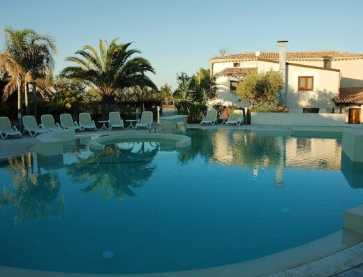 Piscina rilassante con lettini al sole presso l'Agriturismo Baglio San Nicola, un'oasi di pace per viaggiatori in cerca di relax.