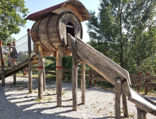 Area giochi per bambini con scivolo in legno e struttura a forma di botte all'Agriturismo Barbati, ideale per famiglie in vacanza.