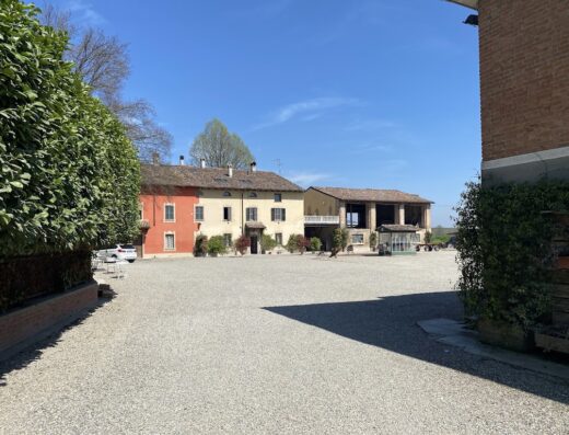 Agriturismo Boschi Celati: vista esterna della struttura con vialetto di ghiaia, edifici colorati e vegetazione circostante.