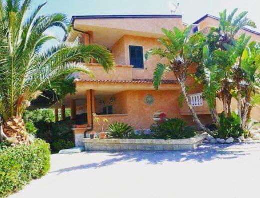 Agriturismo Brace: Facciata esterna della struttura con palme e vegetazione lussureggiante, ideale per un soggiorno rilassante.