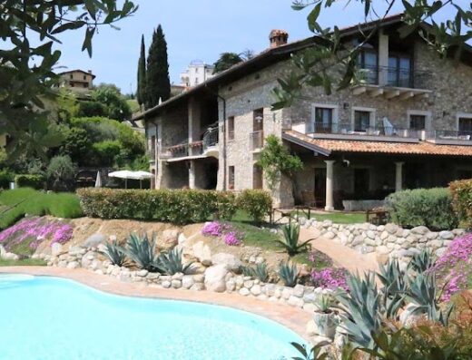 Agriturismo Cascina Crocelle: Vista esterna della cascina con piscina, circondata da un giardino curato con fiori e piante ornamentali.