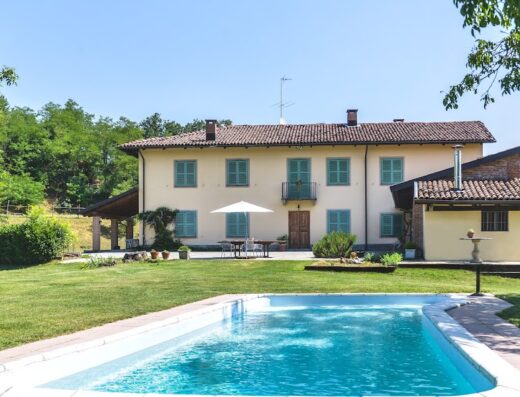 Agriturismo Cascina Lissona: A beautiful farmhouse with a swimming pool and lush green lawn, perfect for a relaxing travel experience in Italy.