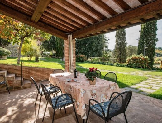 Agriturismo Case Graziani: Outdoor dining area with table set for a meal, chairs, and a view of the Tuscan countryside. Perfect for a relaxing vacation in Italy.