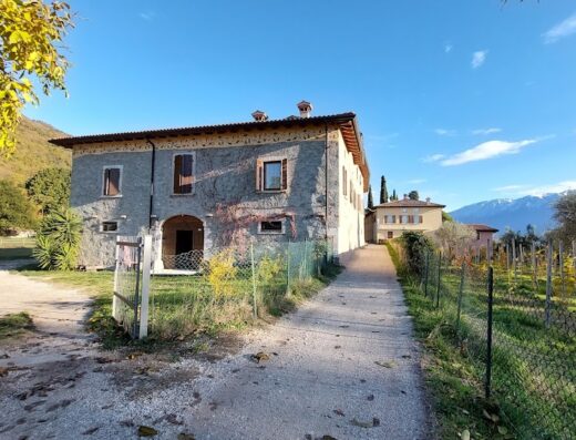 Exterior view of Agriturismo Cervano, a charming Italian farmhouse surrounded by vineyards and mountains, offering a serene travel destination.