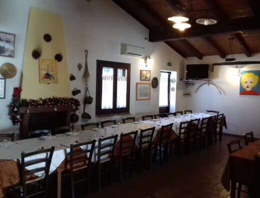 Dining room at Agriturismo Colle Bianco, featuring a long table set for a large group, a fireplace, and rustic decor.