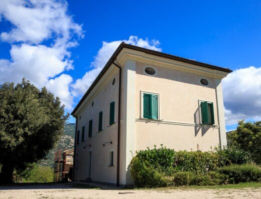 Agriturismo Colle Tocci a Subiaco: Veduta esterna della struttura con cielo azzurro e nuvole bianche. Facciata con finestre verdi e vegetazione circostante.