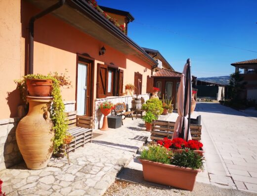 Agriturismo Collina di Roseto: Esterno accogliente con vasi di fiori, panchine in legno e un grande vaso decorativo, tipico dell'ospitalità italiana.