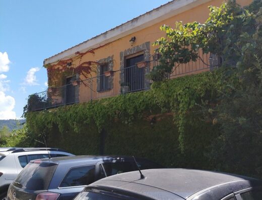 Agriturismo Corbella: Esterno della struttura con balcone fiorito, auto parcheggiate e cielo azzurro. Ideale per vacanze e soggiorni in agriturismo.