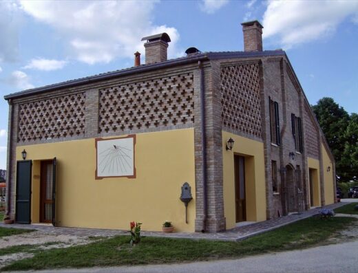 Agriturismo Corte dei Maghi: Veduta esterna della struttura con facciata gialla, dettagli in mattoni a vista e meridiana.