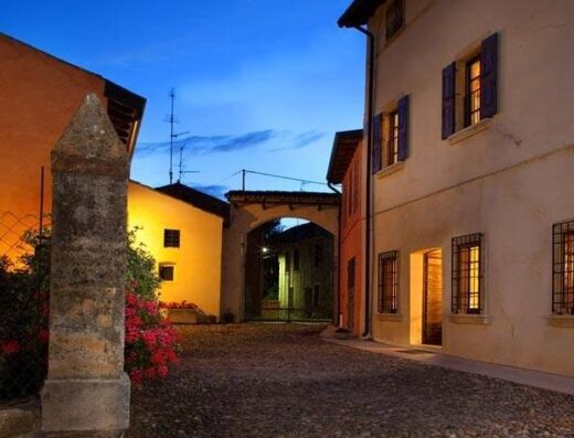 Agriturismo Corte Olfino: Scorcio serale suggestivo con pavimentazione in ciottoli, illuminazione calda e architettura tradizionale italiana.