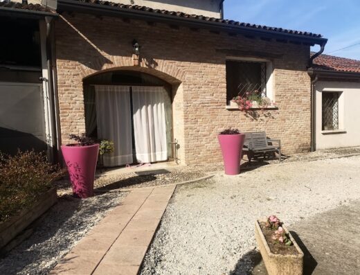 Corte Rocca Agriturismo: Esterno in pietra con vasi fucsia, panchina e fiori, tipico casale di campagna italiano.