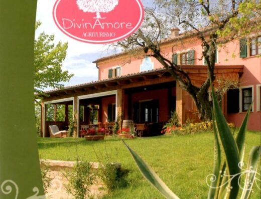 Agriturismo Divin Amore: vista esterna della struttura con giardino curato, ideale per vacanze rilassanti nelle colline marchigiane.