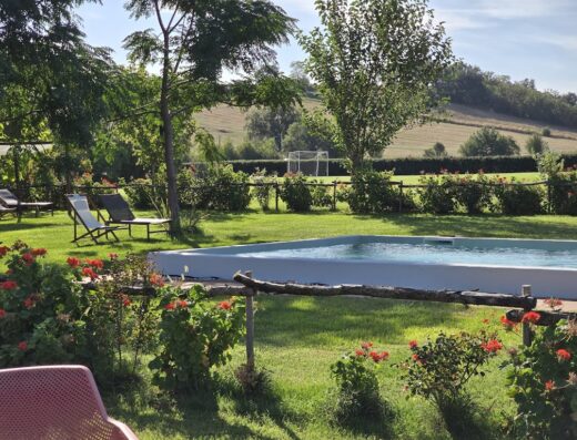 Agriturismo ESSENTIA Dimora Rurale: Vista rilassante sulla piscina, i prati verdi, le colline e un campo da calcio.