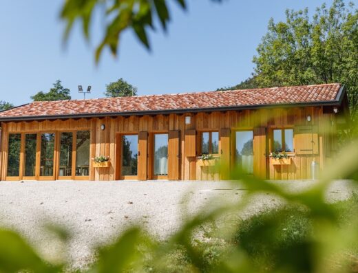 Agriturismo Fattoria Carolina: Exterior view of a wooden building with terracotta roof tiles, surrounded by greenery, showcasing the rural charm of the location.