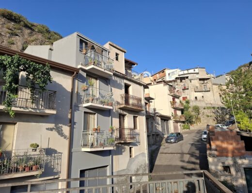 Agriturismo Fondo Cipollate: Facciata di case tipiche con balconi fioriti in un borgo collinare siciliano, dettaglio architettonico e atmosfera accogliente.