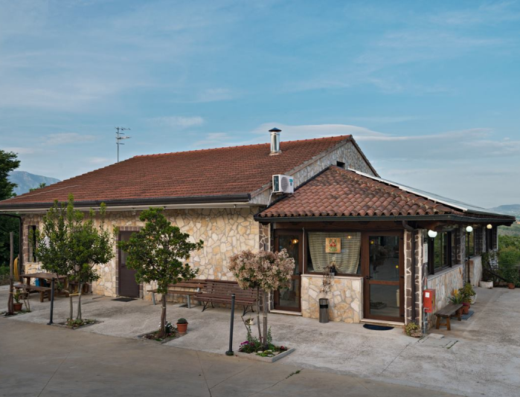 Agriturismo Fontana Lauri exterior view featuring stone facade, tiled roof, outdoor seating, and scenic landscape in Italy, promoting rural tourism and accommodation.