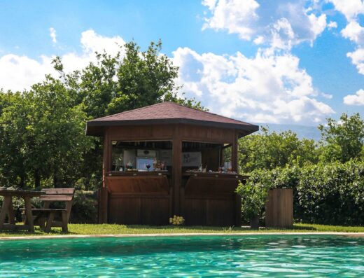 Bar all'aperto in legno con piscina all'Agriturismo Galea, ideale per un aperitivo rilassante nella campagna italiana.