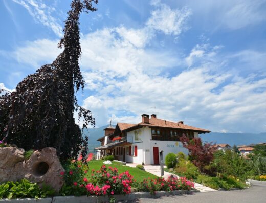 Agriturismo Golden Pause exterior view, showcasing the building, gardens, and mountain backdrop, ideal for a motorcycle travel stop.