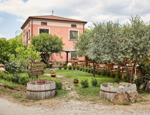 Exterior view of Agriturismo I Moresani, featuring a garden, restaurant sign, and outdoor dining area in Italy. Travel destination and culinary experience.