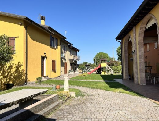 Agriturismo Il Bortolino: Esterno con area giochi per bambini, edifici colorati e vialetto acciottolato in una giornata di sole.