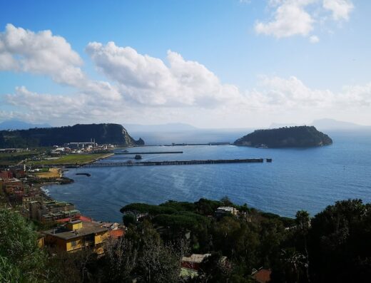 Veduta panoramica di Bacoli e Procida dall'Agriturismo Il Gruccione, con case colorate, mare blu e cielo nuvoloso.