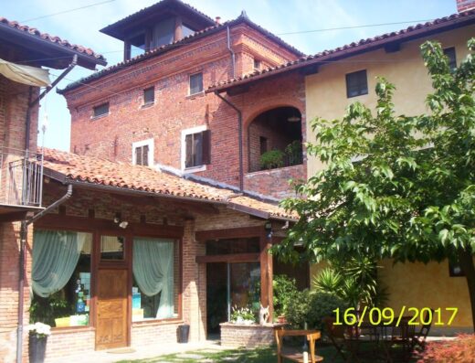 Agriturismo Il Palazzetto: Immagine esterna dell'agriturismo con edifici in mattoni rossi, un cortile verde e arredi da esterno.