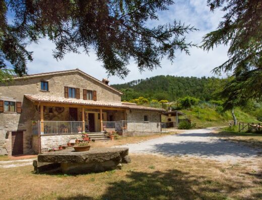 Agriturismo Il Principe Contadino: Veduta esterna della struttura in pietra con portico e giardino curato, immersa nel verde della campagna toscana.
