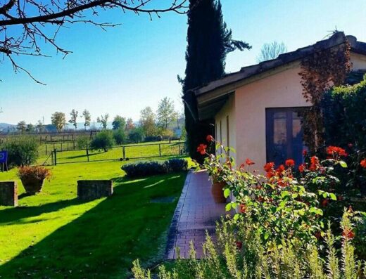 Agriturismo Il Sole Verde: Vista panoramica della casa colonica con giardino curato, cipresso e vegetazione rigogliosa in Toscana.