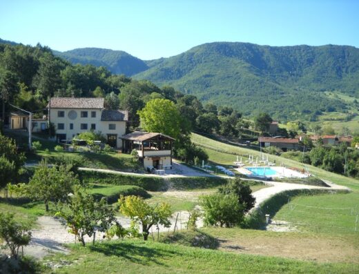 Agriturismo La Concia: Panorama della struttura con piscina, vegetazione rigogliosa e montagne sullo sfondo.