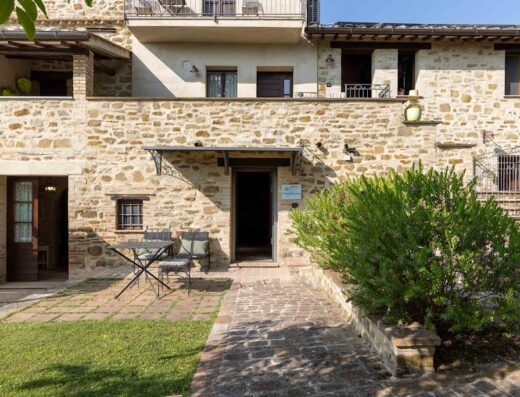 Agriturismo La Palazzetta di Assisi: Exterior view of the stone building showcasing the entrance, outdoor seating, and garden area, typical of a rural Italian vacation rental.