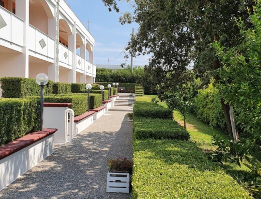Agriturismo La Rondine a Otranto: Esterno dell'agriturismo con vialetto curato, siepi geometriche, panchine e illuminazione esterna.