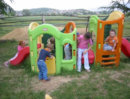 Bambini che giocano su una struttura da gioco colorata all'aperto all'Agriturismo La Villa, godendosi un'esperienza divertente in campagna.