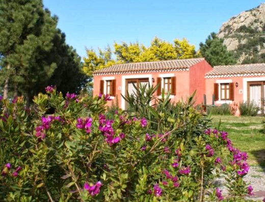 Agriturismo l'Aglientu di Antonella Bonacossa: vista esterna di un edificio rosa con fiori in primo piano, tipico della regione.
