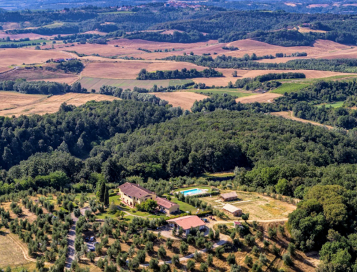 Aerial view of Agriturismo L'Antica Fornace in Tuscany, Italy, showcasing the farmhouse, pool, olive groves, and surrounding landscape