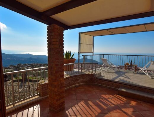 Terrazza panoramica dell'Agriturismo Le Agavi a Cilento con vista mare, sdraio, tavolino con vino. Ideale per relax e vacanze.