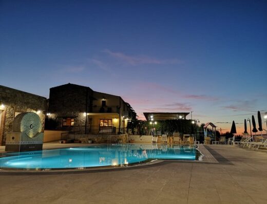 Agriturismo Le Campanelle: Serene view of the pool area at dusk, featuring stone buildings, lounge chairs, and a peaceful atmosphere.